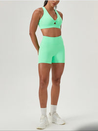 Person wearing a green sports bra and shorts set on a white background