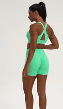 Person wearing a bright green sports bra and shorts set on a white background