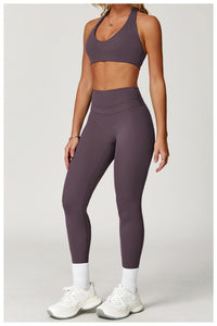 Person wearing a purple sports bra and leggings set with white sneakers on a light gray background