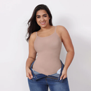 Woman wearing a beige tank top and blue jeans against a white background